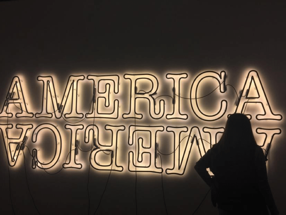 Student standing in front of America neon sign